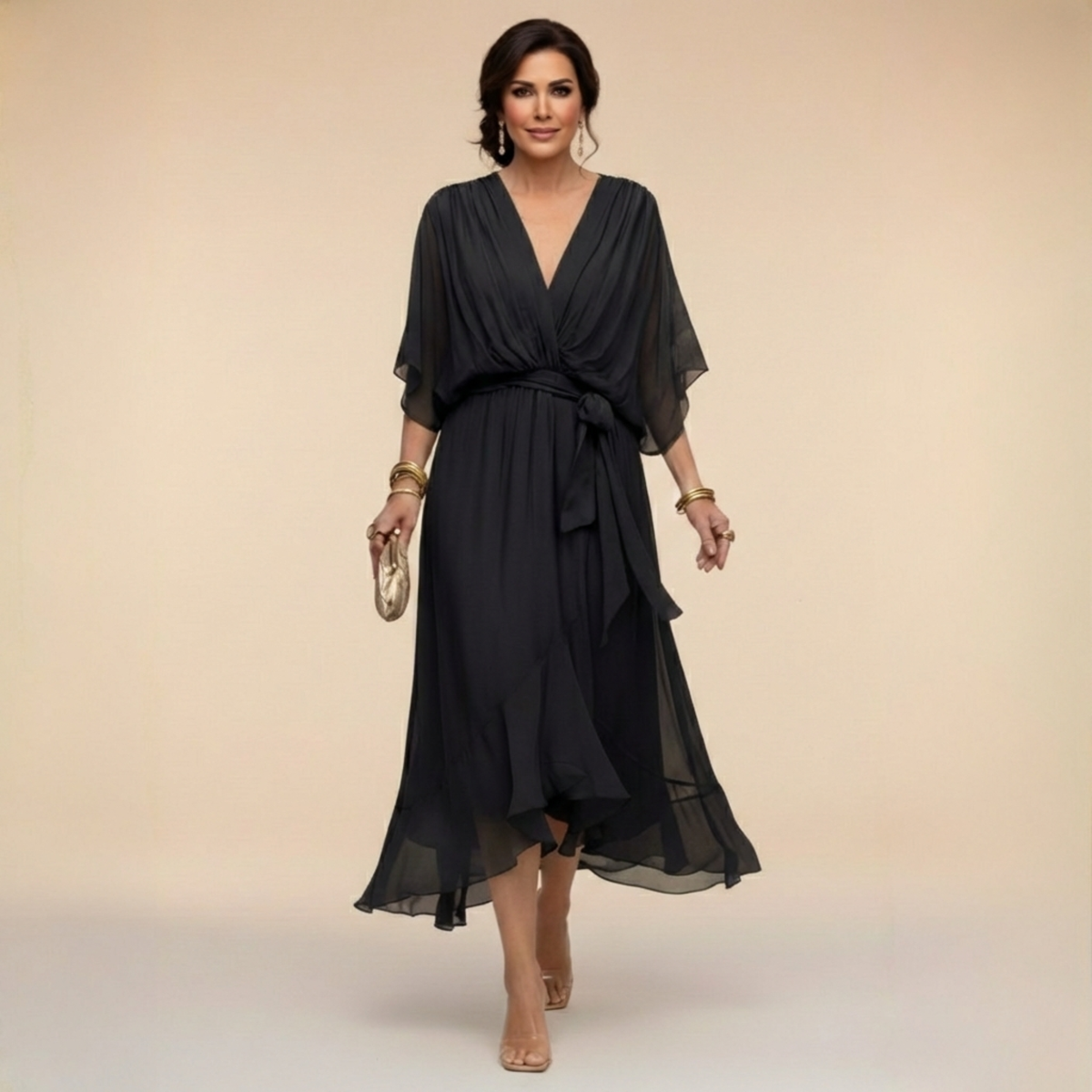 Woman wearing a black dress with sheer sleeves against a beige background