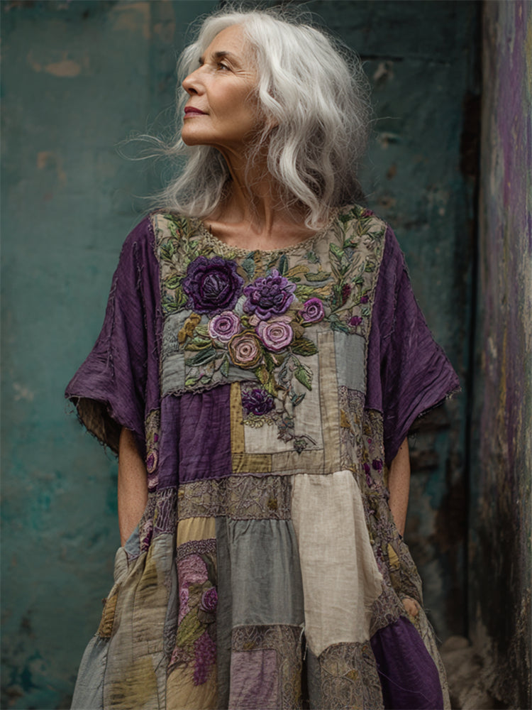 Woman wearing a patchwork dress with floral patterns against a textured green wall.