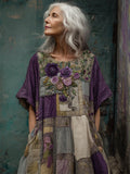 Woman wearing a patchwork dress with floral patterns against a textured green wall.