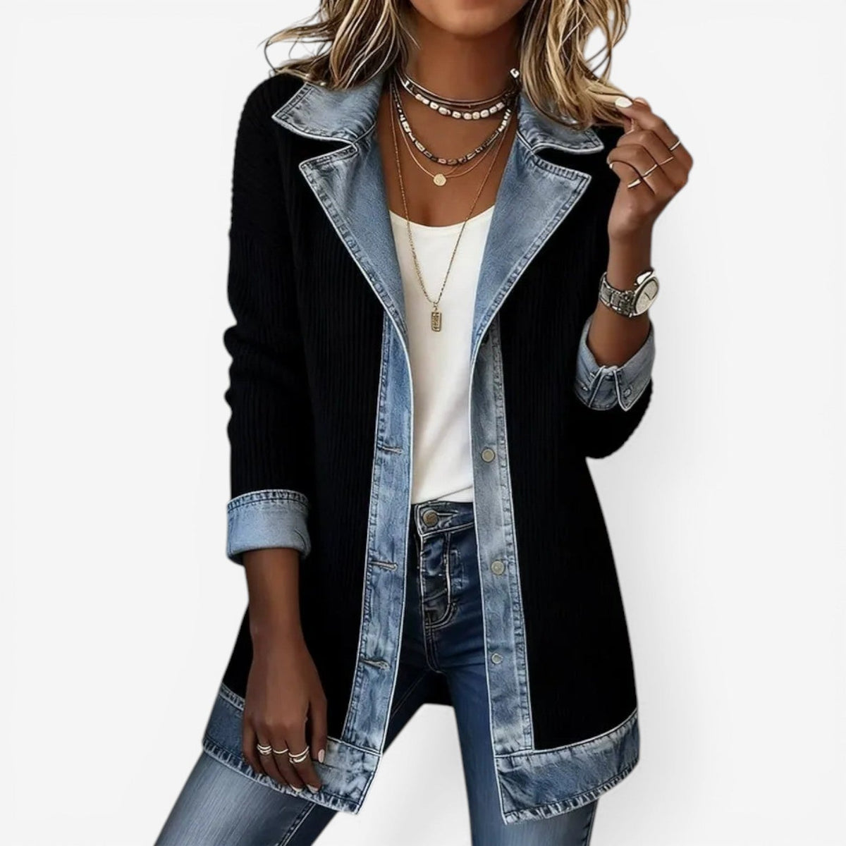 Person wearing a black jacket with denim trim on a white background